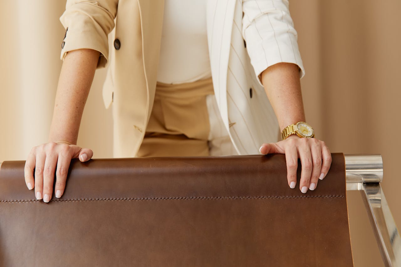 immagine due mani femminili che tengono lo schienale di una elegante poltrona di pelle