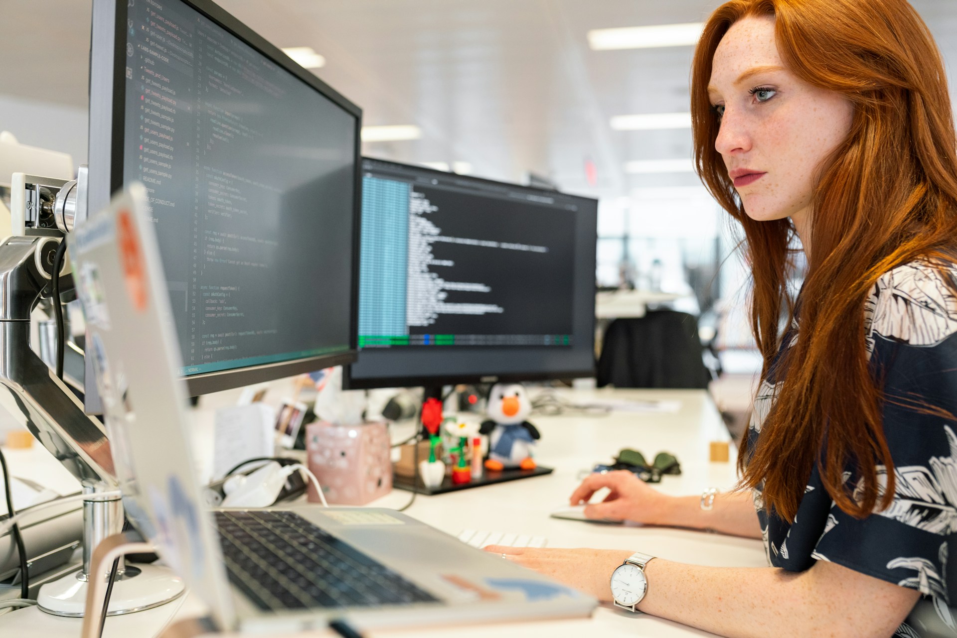 donna che lavora al computer con davanti tanti schermi diversi